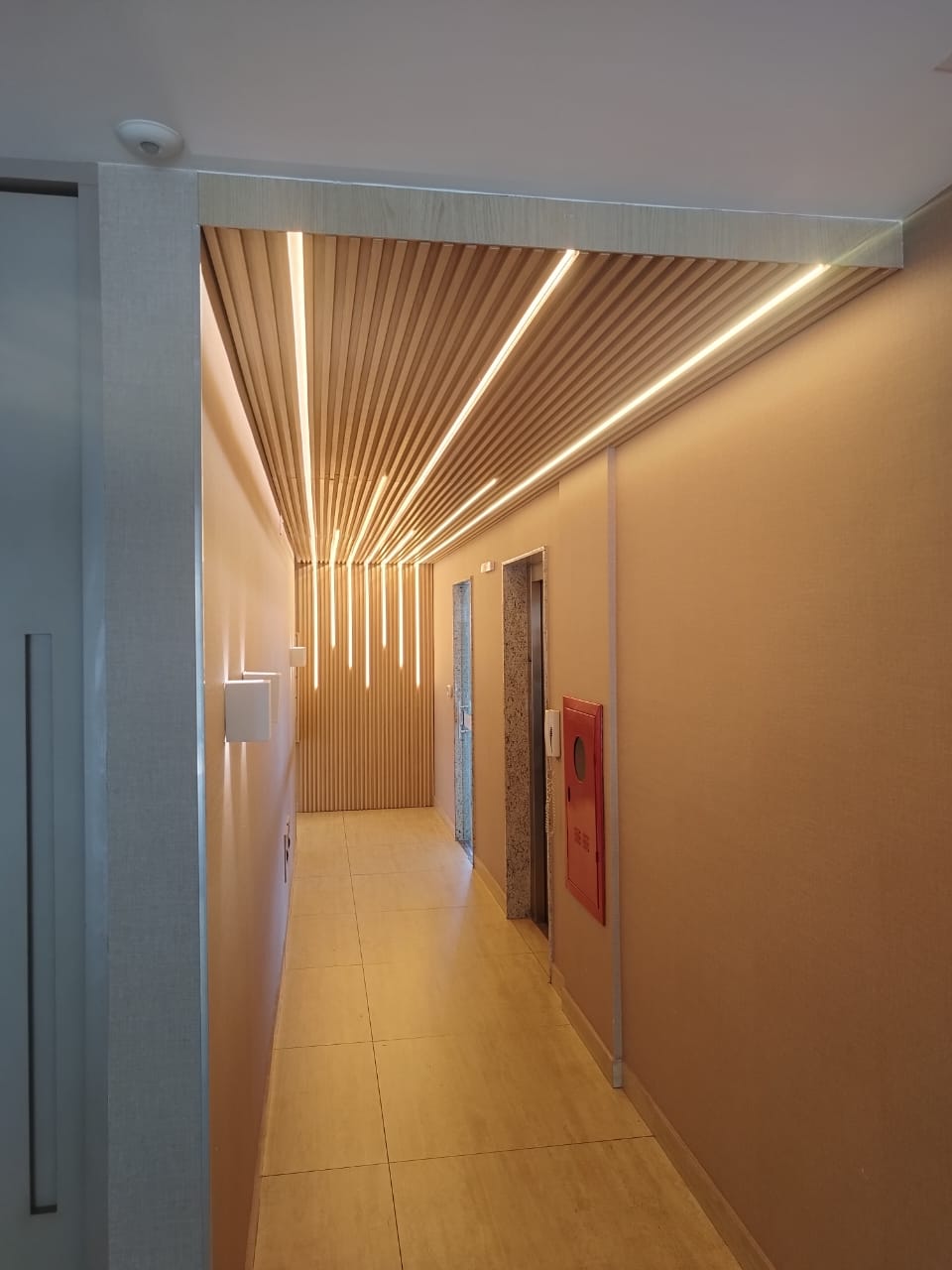 Corredor com painel ripado iluminado — projeto Estilo Armários Planejados